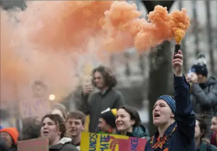  ?? Emily Matthews/Post-Gazette photos ?? Faith Ruck, a junior studying environmen­tal studies at the University of Pittsburgh and a co-organizer of Fossil Free Pitt Coalition, sets off an orange smoke bomb during Thursday's rally.