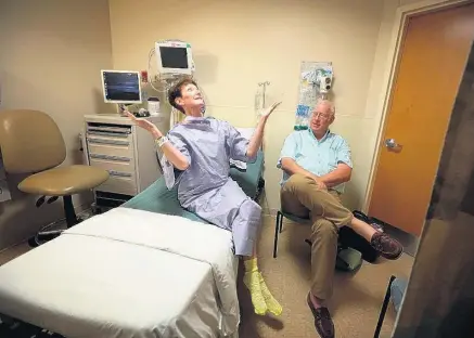  ?? STEVE EARLEY PHOTOS/STAFF FILES ?? Jane Gardner laughs with her husband, Gary, about how she looks in her hospital gown, one that she had trouble figuring out how to put on and ended up with a bow beneath her neck like a bow tie, at Sentara Leigh Hospital in 2015.