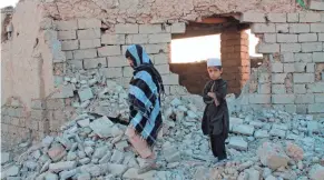  ?? ABDUL KHALIQ/AP ?? Afghan boys walk near a house that was damaged by airstrikes two weeks earlier, Saturday in Lashkar Gah, Afghanista­n.