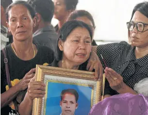  ?? REUTERS ?? A woman cries as she holds a portrait of her family member who was among the 15 people, mostly village defence volunteers, killed in Tuesday night’s attack on a security checkpoint in Yala’s Muang district. She was attending a funeral that was held yesterday.
