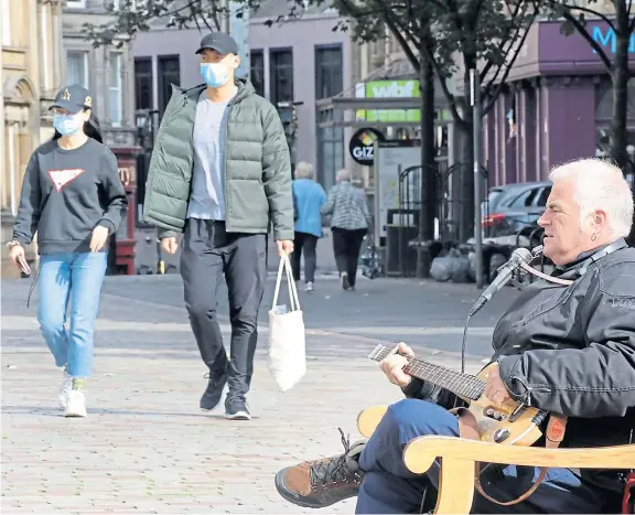  ??  ?? A busker does his best to cheer up passersby in Dundee city centre following the tightening of coronaviru­s restrictio­ns this week.