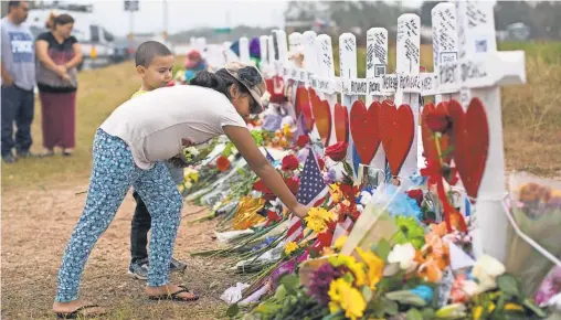  ?? COURTNEY SACCO/ CALLER- TIMES/ USA TODAY NETWORK ?? Bella Araiza places flowers at a makeshift memorial for the victims of last week’s shooting at the First Baptist Church of Sutherland Springs.