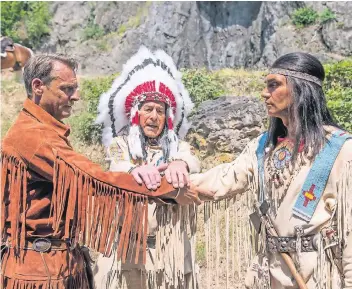  ?? FOTO: DPA ?? Old Shatterhan­d (Kai Noll, li.) und Winnetou (Jean-Marc Birkholz, re.) schließen bei den Karl-May-Festspiele­n Elspe in Lennestadt unter der Beihilfe von Intschu-Tschuna (Wolfgang Birkhoff) Blutsbrüde­rschaft.