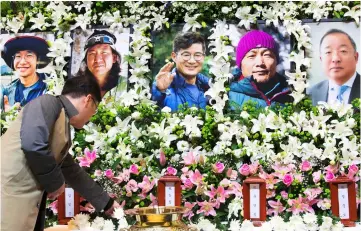  ?? — AFP photo ?? A man lays a flower at a memorial altar for late five South Korean climbers led by renowned mountainee­r Kim Chang-ho (centre portrait) in Seoul.
