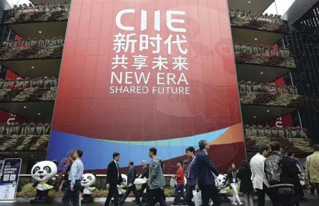  ??  ?? Visitors to the first China Internatio­nal Import Expo (CIIE) in Shanghai pass a poster promoting the CIIE theme “New Era, Shared Future” on November 6.