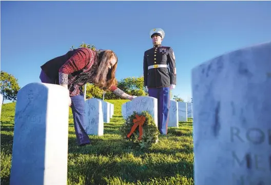  ?? NELVIN C. CEPEDA U-T PHOTOS ?? Master Gunnery Sgt. Jason Edwards stands watch until Shannon Edwards places a wreath at the grave of Gunnery Sgt. Michael Passaro at Miramar National Cemetery on Saturday.