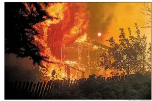 ?? AP/NOAH BERGER ?? Flames from a wildfire consume a home Tuesday in Lakeport, Calif.