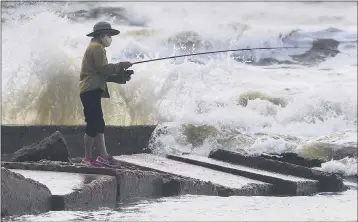  ?? STUART VILLANUEVA — THE GALVESTON COUNTY DAILY NEWS ?? Waves crash as Houston resident Tinh Pham fishes from the rocks at Diamond Beach in Galveston, Texas, on Saturday.