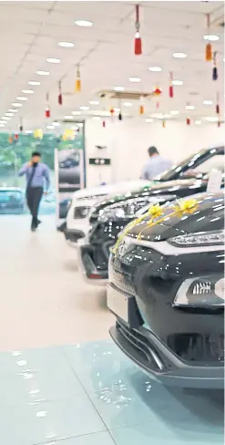  ??  ?? MAIN PHOTO
A sign for Kona electric vehicle stands next to vehicles at Koncept Hyundai showroom in New Delhi.