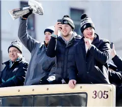  ?? AFP ?? Eagles quarterbac­k Nick Foles hoists the Vince Lombardi Trophy as team owner Jeffrey Lurie, left, Nate Sudfeld, second right, and Carson Wentz ride on a parade truck.