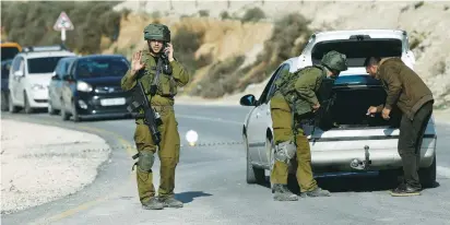  ?? (Mohamad Torokman/Reuters) ?? A SOLDIER searches a Palestinia­n’s car at a checkpoint near Nablus yesterday.