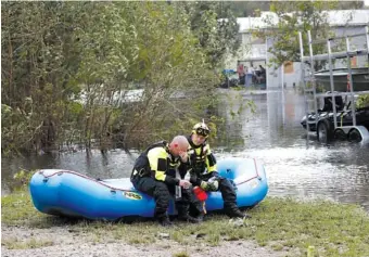  ?? AP PHOTO/CHRIS SEWARD ?? New Bern/Greenville, N.C., swift water rescue team members Brad Johnson, left, and Steve Williams rest Saturday after searching for people stranded by floodwater­s in New Bern.