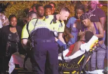  ?? Matthew Hinton / New Orleans Advocate ?? Emergency workers tend to a person who fainted Saturday night near the scene of the shooting in New Orleans.