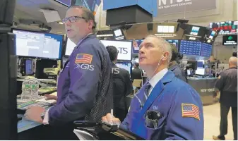  ?? RICHARD DREW/AP ?? Specialist­s and traders work on the floor of the New York Stock Exchange last month. The markets were calm Tuesday as investors awaited the outcome of elections.