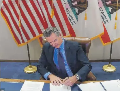  ?? OFFICE OF THE GOVERNOR VIA AP, FILE ?? California Gov. Gavin Newsom signs into law a bill that establishe­s a task force to come up with recommenda­tions on how to give reparation­s to Black Americans on Sept. 30, 2020, in Sacramento, Calif.