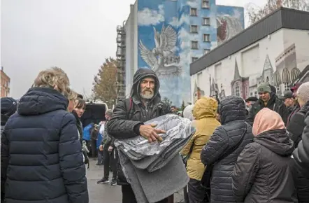  ?? — AFP ?? Winter is here: People taking blankets and lamps during an aid supply distributi­on in Kherson.