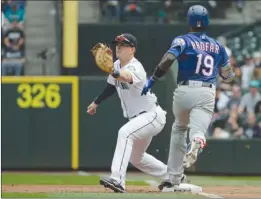  ?? The Associated Press ?? Seattle Mariners first baseman Ryon Healy reaches for the throw in time to get Texas Rangers’ Jurickson Profar (19) out during Wednesday’s game in Seattle.