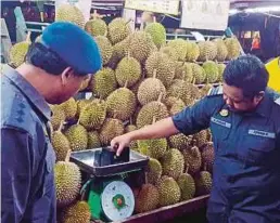  ??  ?? PEGAWAI KPDNKK memeriksa alat penimbang di beberapa gerai durian.