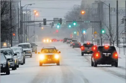  ?? Tom Stromme ?? The Associated Press Traffic moves cautiously down a snow-covered street in Bismarck, N.D., on Monday. Freezing rain, heavy snow and strong winds blew into the northern Plains, impacting travel, schools and government offices.