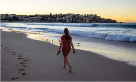  ?? Photograph: Jenny Evans/Getty Images ?? A woman walks along Bondi beach. While many workers have been forced to take time off during the pandemic, others are working harder than ever.