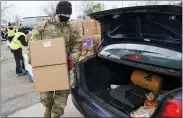  ?? THE ASSOCIATED PRESS ?? Staff Sgt. Mike Schuster loads two produce boxes into a car at a food bank distributi­on by the Greater Cleveland Food Bank.