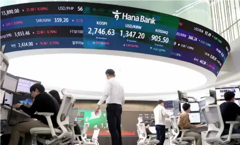  ?? YONHAP/ VNA Photo ?? O cials work at a dealing room of Hana Bank in central Seoul. South Korea's Kospi
gained 2 per cent yesterday.