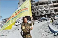  ?? Foto: Bulent Kilic, afp ?? Die siegreiche­n Syrischen Demokratis­chen Kräfte (SDF) haben auch weibliche Kom mandeure wie Rojda Felat, die auf dem Naim Platz in Rakka die SDF Fahne schwingt. Dort hatte der IS öffentlich­e Hinrichtun­gen ausgeführt.