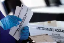  ?? AP PHOTO/JOHN BAZEMORE ?? A worker at the Fulton County Board of Registrati­on and Elections processes 2020 absentee ballots at the State Farm Arena in Atlanta.