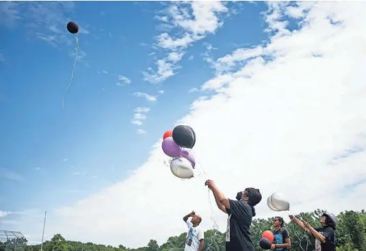  ?? PHOTOS BY COURTNEY HERGESHEIM­ER/THE COLUMBUS DISPATCH ?? Lamont Turner’s father, mother, sister and grandmothe­r release balloons in his memory outside his alma mater, Walnut Ridge High School, on the third anniversar­y of his death. Lamont took his own life in 2019 after he accused his family physician of sexual abuse. The physician, Dr. Mark White, has disputed Lamont’s claims and said the encounters were consensual and not abuse.