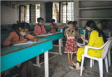  ?? Altaf Qadri Associated Press ?? STUDENTS attend class on the first day of partially reopened school in Noida, a suburb of New Delhi, this month. In rural parts of India, the pandemic is reversing progress toward lifting children out of poverty.