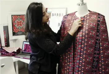  ?? MAHMOUD ILLEAN ?? Natalie Tahhan works on designs in her East Jerusalem studio, aiming to connect tradition with what is “new and stylish.” She produces capes from digital prints replicatin­g traditiona­l embroidery stitches.