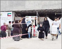  ?? KUNA photo ?? Iraqis wait in line as Kuwait distribute­s 60 tons of food in Iraq’s Kurdistan.