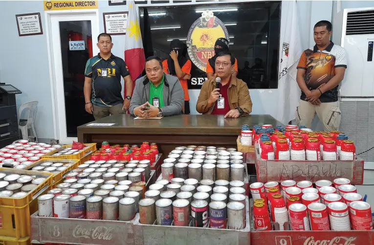  ?? Intelligen­ce BING GONZALES ?? NATIONAL Bureau of Investigat­ion XI agent Juhary Guro and Officer Don Albert Faustino brief reporters on the seized 908 illegally refilled butane canisters from two arrested vendors in an entrapment operation in Bankerohan Public Market on Monday afternoon, Feb. 19, 2024, following a complaint from an LPG manufactur­er.