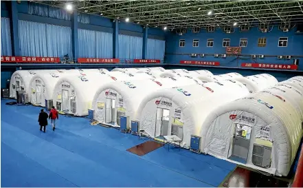  ?? AP ?? Workers walk past a temporary Covid-19 testing laboratory built on an indoor tennis court in Shijiazhua­ng in northern China’s Hebei Province.