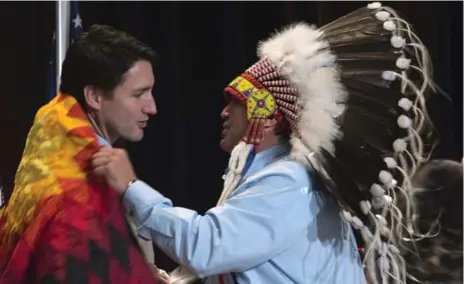  ?? CHRIS WATTIE/REUTERS ?? Assembly of First Nations National Chief Perry Bellegarde adjusts a blanket presented to Prime Minister Justin Trudeau in Gatineau, Que., Tuesday.