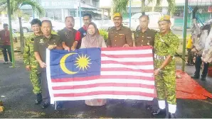  ??  ?? PENYERAHAN Jalur Gemilang kepada anggota Rela Daerah Tawau oleh Hamisa.