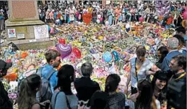  ?? OLI SCARFF/GETTY-AFP ?? People in Manchester’s St. Ann’s Square, where floral tributes grew by the hour, observe a minute of silence Thursday for victims of Monday’s pop concert attack, which killed 22.