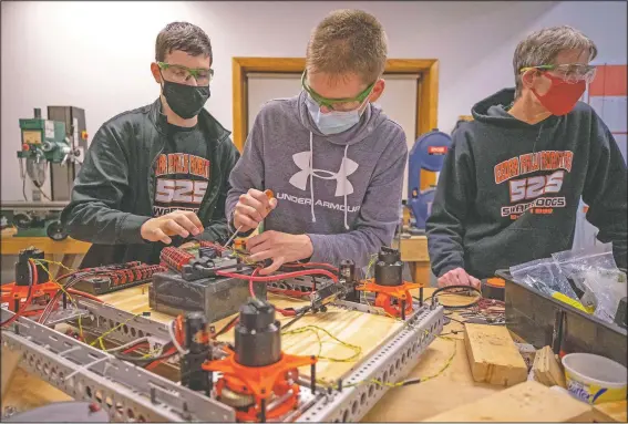  ?? (Waterloo-Cedar Falls Courier/Chris Zoeller) ?? FIRST Robotics Competitio­n Team 525 members Sean Radke (from left) and Carson Anton work on a robotics project as Cedar Falls High School FIRST Robotics Competitio­n coach Kenton Swartley supervises at the team’s workspace in the Cedar Falls industrial park.