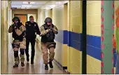  ?? Associated Press ?? ■ In this Jan. 28, 2013, file photo, members of the Washington County Sheriff’s Office and the Hudson Falls Police Department use unloaded guns to take part in an emergency drill as they walk through a corridor inside the Hudson Falls Primary School in Hudson Falls, N.Y.