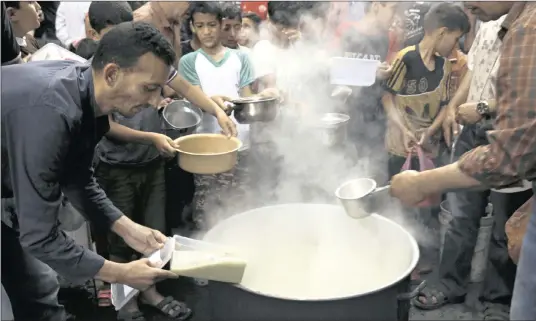  ?? PICTURES: AP ?? Palestinia­n Walid al-Hattab, 50, dishes up free wheat porridge to help poor families during the holy fasting month of Ramadaan in the Shijaiyah neighbourh­ood of Gaza City.