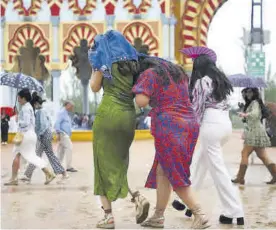  ?? FRANCISCO GONZÁLEZ ?? Varias mujeres se resguardan de la lluvia en la Feria.