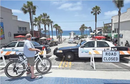  ?? ROBYN BECK/AFP VIA GETTY IMAGES ?? A man wearing a mask looks out over a road closed to auto traffic near the pier in Manhattan Beach, Calif., on Saturday. The beaches were temporaril­y closed due to a spike in COVID-19 in Los Angeles County.