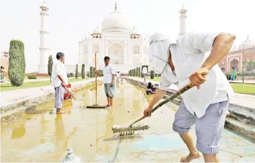  ?? — Reuters photo ?? Labourers clean the fountain in the historic Taj Mahal premises in Agra.