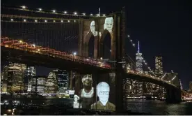  ??  ?? The faces of Brooklyn residents who died from Covid are remembered with photograph­s projected on to Brooklyn Bridge, New York on 14 March. Photograph: Reuters