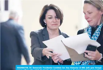  ?? —AFP ?? WASHINGTON, DC: Democratic Presidenti­al Candidate Sen Amy Klobuchar (D-MN) (left) goes through papers with in aide outside the Senate chamber during a recess in the impeachmen­t trial proceeding­s against President Donald Trump at the US Capitol on Friday in Washington, DC.