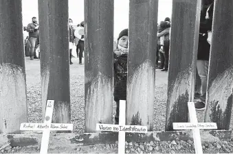  ?? Ross D. Franklin, The Associated Press ?? A young boy, part of several asylum-seeking families participat­ing in a Dec. 15 Las Posadas event at the U.S.-Mexico border wall, peers into the U.S. from Mexico, past crosses rememberin­g those who died trying to cross the border in Douglas, Ariz. Las Posadas is a tradition practiced in Mexico that reenacts Mary and Joseph’s search for refuge in Bethlehem.