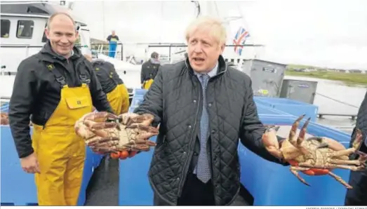  ?? ANDREW PARSONS / DOWNING STREET ?? El primer ministro británico, Boris Johnson, sostiene dos cangrejos junto a un pescador en su visita a los Highlands escoceses.