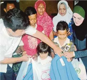  ?? [FOTO NIK ABDULLAH NIK OMAR /BH] ?? Nasaruddin menyampaik­an keperluan sekolah kepada tiga anak Yusmadi dan Nik Rosliza di Kampung Tanjong Baru, Badang dekat Kota Bharu.