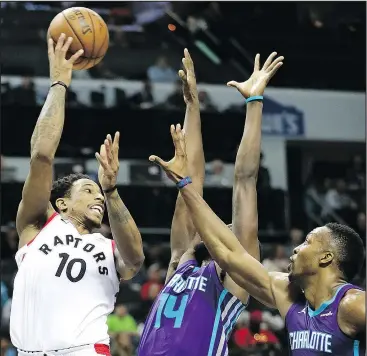  ?? STREETER LECKA/GETTY IMAGES ?? Raptors all-star DeMar DeRozan (left) drives to the basket against the Hornets’ Dwight Howard (right) and Michael Kidd-Gilchrist on Sunday. DeRozan had 25 points in the win.