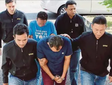  ?? PIC BY AMRAN HAMID ?? MACC officers escorting the two suspects at the Alor Star magistrate’s court yesterday.